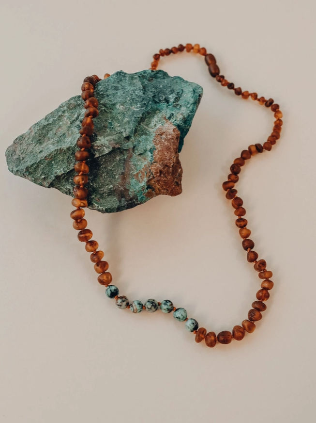 This Raw Cognac Baltic Amber + Turquoise Jasper Beaded Necklace by CanyonLeaf is handmade using original Baltic Sea Amber that is over 45 million years old. Baltic Amber has some of the highest concentrations of Succinic Acid found in nature and this is what makes it so special. Fossilized tree sap that has been preserved for millions of years under the sea. It is a true gift from Mother Nature.&nbsp;